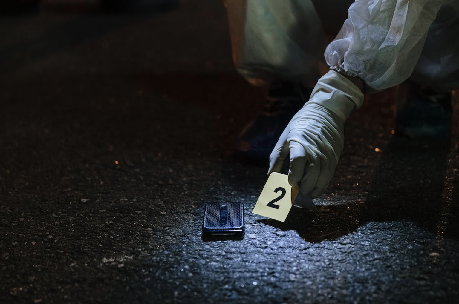 A mobile phone on a crime scene, labeled as evidence by forensics